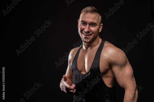 Weight lifter pointing finger and smiling on black background