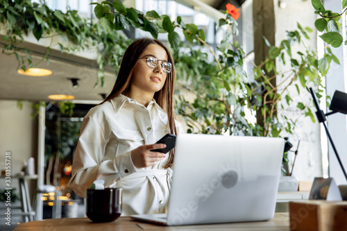 Charming girl working on laptop during breakfast at cafe
