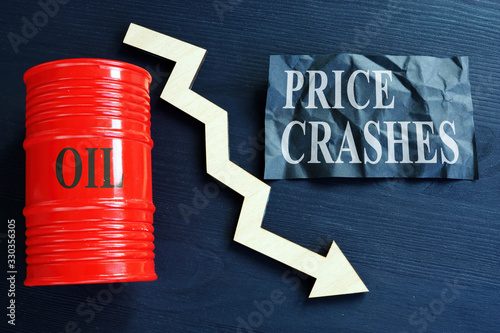 Price crashes sign and crude oil barrel with falling arrow. photo