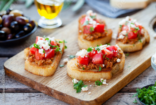 Bruschetta with olive tapenade and fresh tomatoes on cutting board. Wooden background.