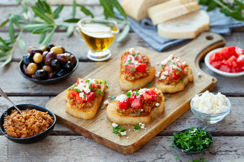 Bruschetta with olive tapenade and fresh tomatoes on cutting board. Wooden background.