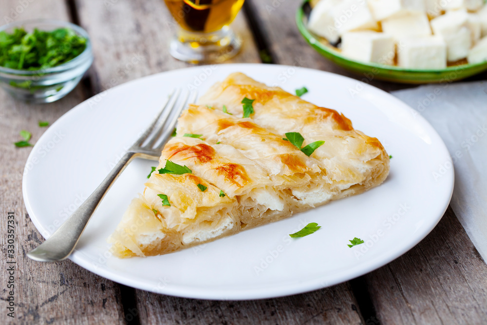 Traditional feta cheese phyllo pastry pie, banitsa. Wooden background. Close up. Traditional feta cheese phyllo pastry pie, banitsa. Wooden background. Close up.