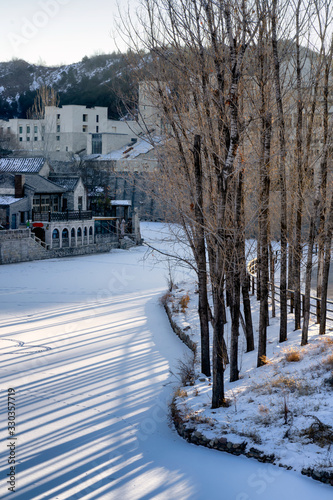 Morning sun shining through the trees snow covered the river at Gubei water town in Beijing,China. photo