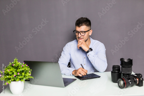 Young handsome man photo editor using graphics tablet in office