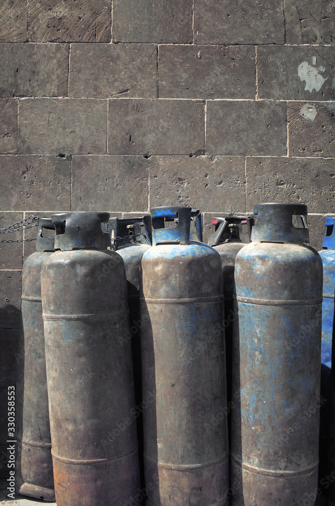 Group of old gas cylinders against a gray block wall Group of old gas cylinders against a gray block wall