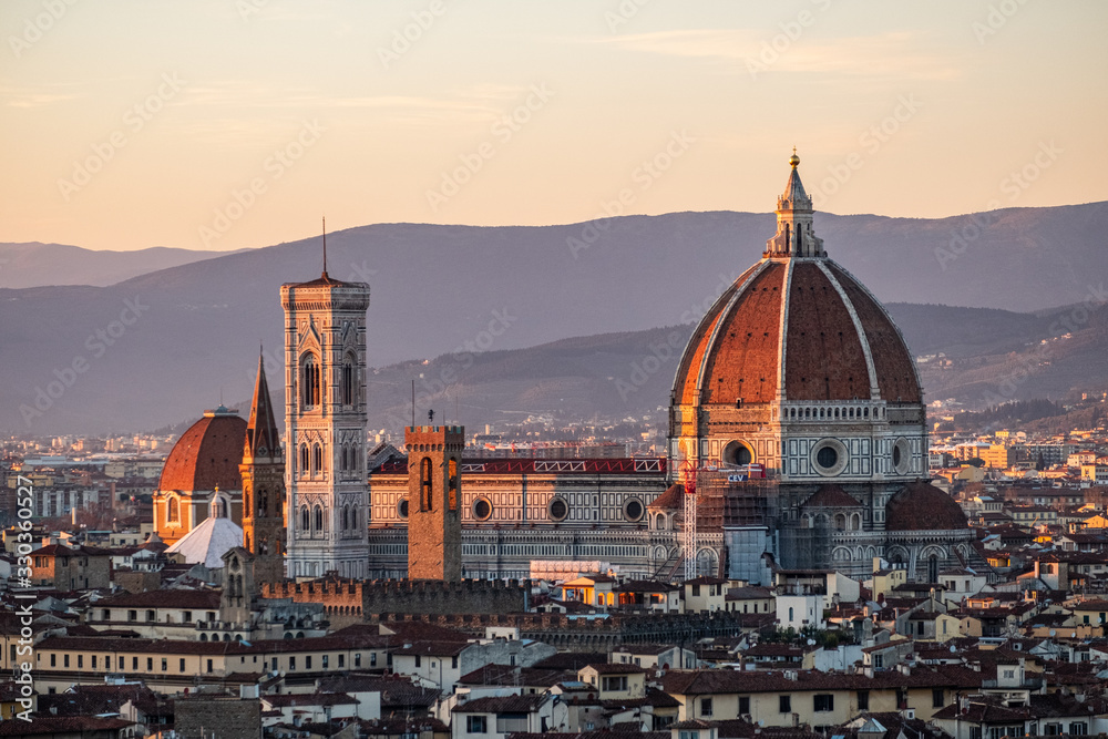 A giant cathedral with a dome glows in the sunset of Florence