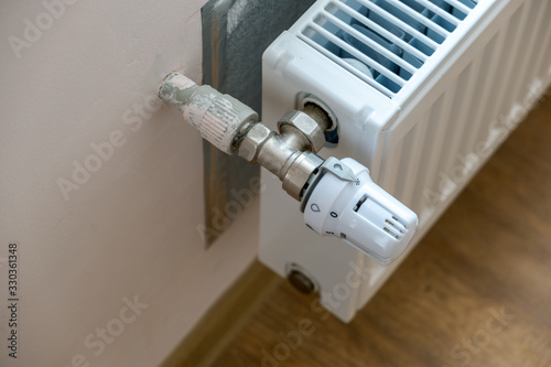 Closeup of heating radiator valve for comfortable temperature regulation on metal radiator on inrerior wall.