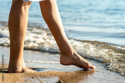 Close up of woman feet walking barefoot on sand leaving footprints on golden beach. Vacation, travel and freedom concept. People relaxing in summer. © bilanol