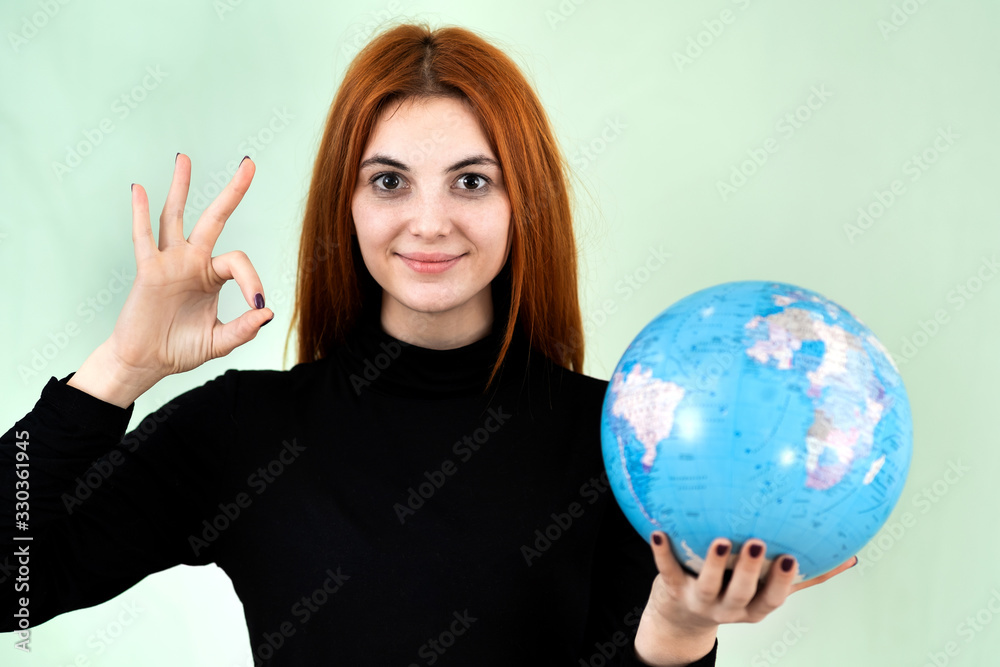 Portrait of a happy young woman holding geographic globe of the world in her hands. Travel destination and planet protection concept. Portrait of a happy young woman holding geographic globe of the world in her hands. Travel destination and planet protection concept.