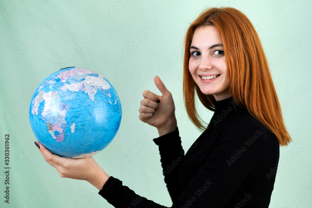 Portrait of a happy young woman holding geographic globe of the world in her hands. Travel destination and planet protection concept. Portrait of a happy young woman holding geographic globe of the world in her hands. Travel destination and planet protection concept.