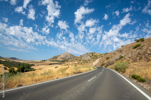 Andalusian landscape with yellow hills and blue sky with high white clouds