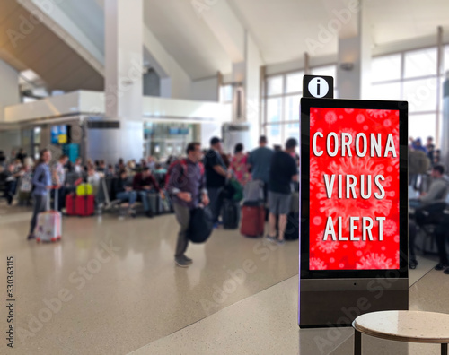 Crowd of people at airport terminal with Corona Virus Sign