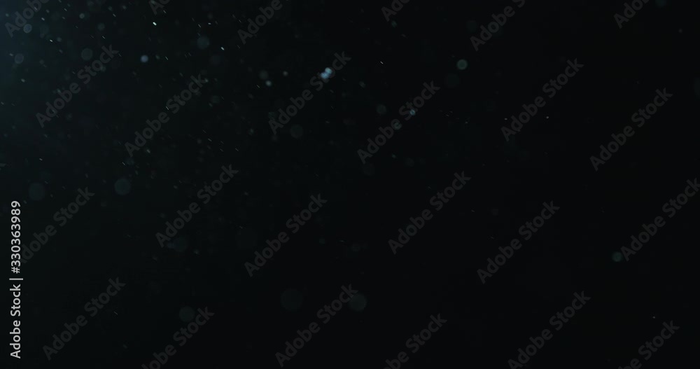 Slow motion natural dust particles flow in air on black background