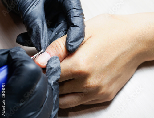 A manicurist  wearing black gloves  does hardware manicure. Cosmetology  hand care  manicure  finger nail care