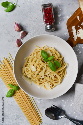 Spaghetti pasta with parmesan cheese and basil in a white plate on a light background top view. gluten free spaghetti recipe homemade pasta. classic Italian cuisine. selective focus