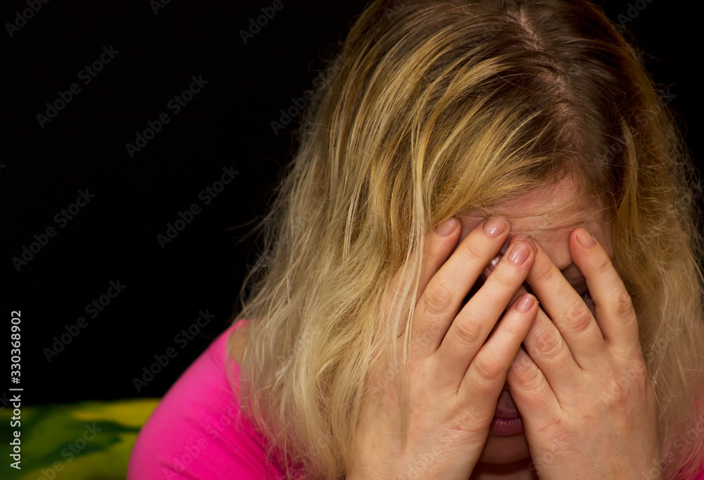 woman who has experienced domestic violence, cries with her hands covered in her face. Black background woman who has experienced domestic violence, cries with her hands covered in her face. Black background