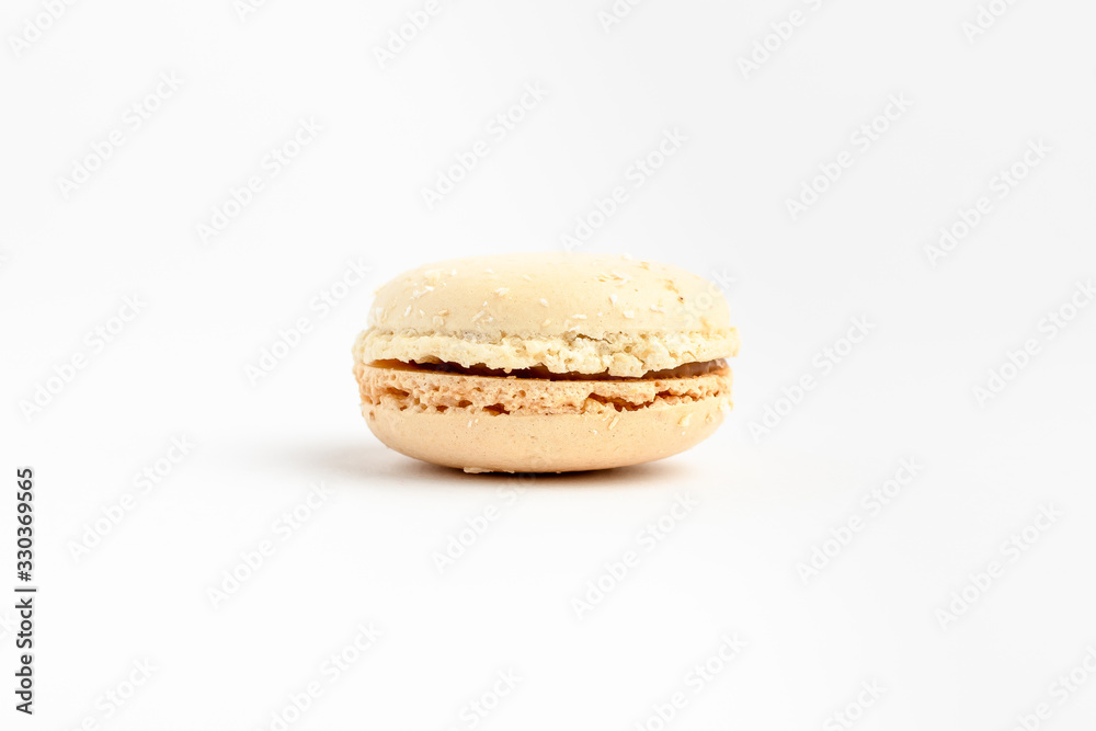 Side view of one sweet white vanilla French macaron isolated on white background, tasty French dessert on a table Side view of one sweet white vanilla French macaron isolated on white background, tasty French dessert on a table