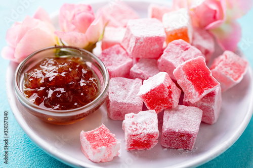 Turkish delight, rose flavour in a white plate. Blue background. Close up.
