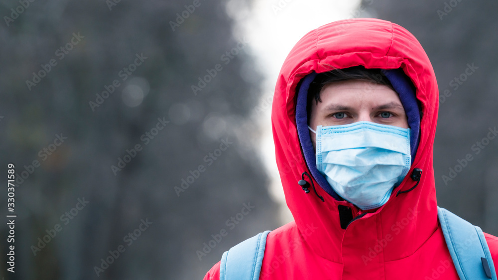 Close-up portrait young europeans man in protective disposable medical face mask walking outdoors. New coronavirus (COVID-19). Close-up portrait young europeans man in protective disposable medical face mask walking outdoors. New coronavirus (COVID-19).