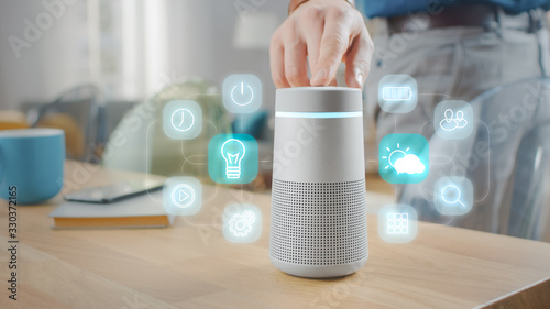 Billede på lærred Man Turns On Smart Speaker with Active Artificial Intelligence Assistant with Futuristic Screenless Interface with Different Icons and Symbols