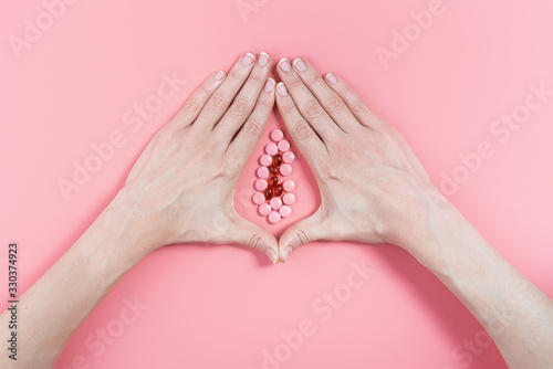 abstract image of female genital organs from hands and pills. concept of women's health and the treatment of female diseases of the urinary tract photo