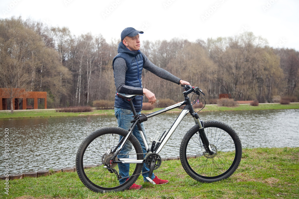 the young man with bicycle in the park in the spring