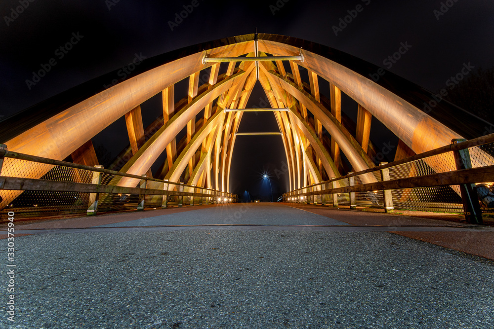 Wooden traffic bridge in the evening with illuminated curved lines and high-up perspective Wooden traffic bridge in the evening with illuminated curved lines and high-up perspective