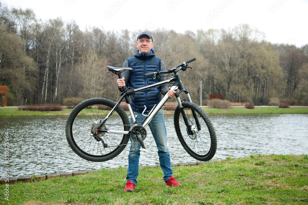 the young man keeps the bicycle in the park in the spring