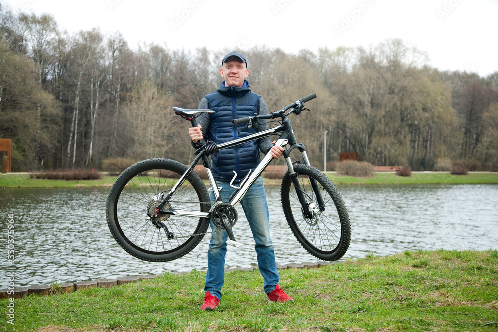 the young man keeps the bicycle in the park in the spring the young man keeps the bicycle in the park in the spring
