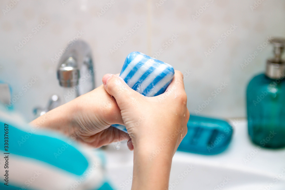 The drop of water from the tap. A man washes his hands in the bathroom. Wash off dirt from hands with water and soap.