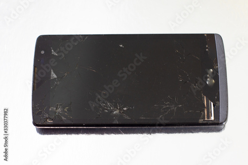 a fallen black smartphone with a shattered screen
