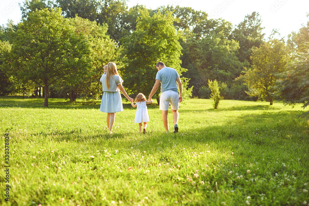 Obraz premium Happy family with children in the park at sunset.