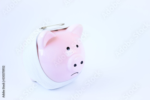 ceramic pink pig with a sad smiley face stands on a white background, the concept of saving money
