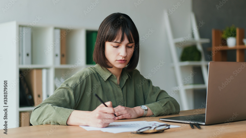 Businesswoman using laptop and writing in notebook Businesswoman using laptop and writing in notebook