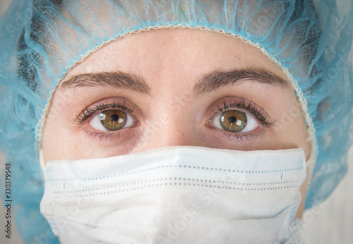 Nurse in a white mask. The face is close. Tired sad eyes of a paramedic after a hard day's work.  slanting eyes.  coronavirus