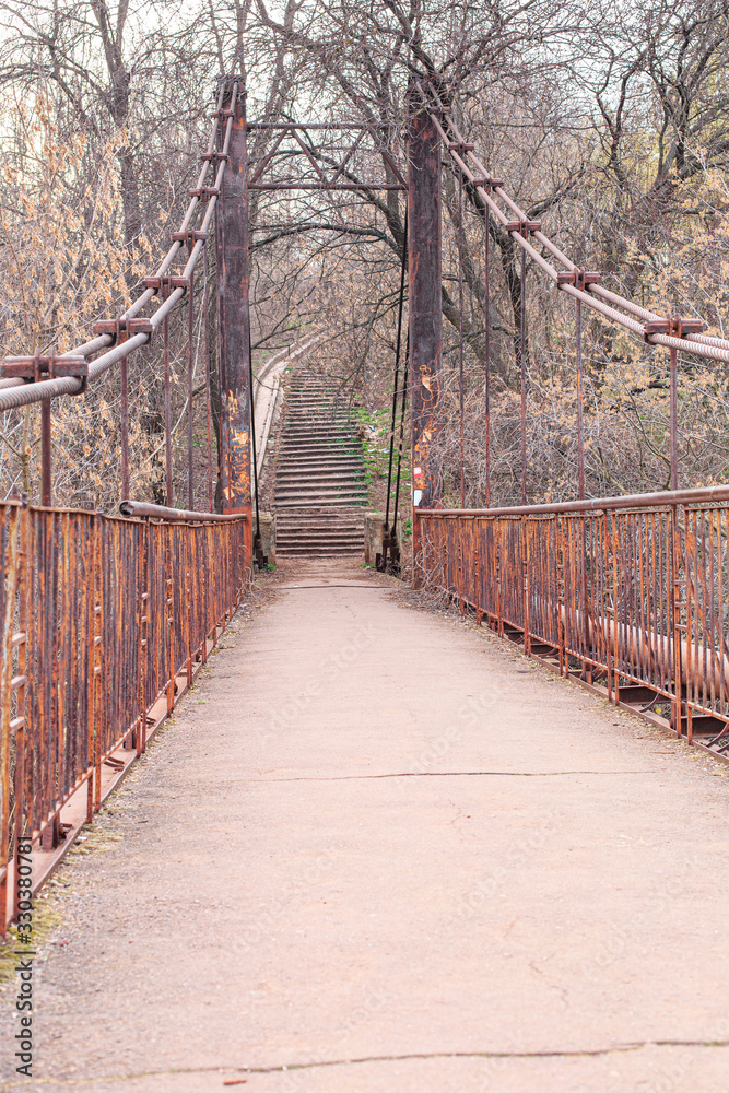 Old pedestrian bridge with rusty railings and rusty poles
