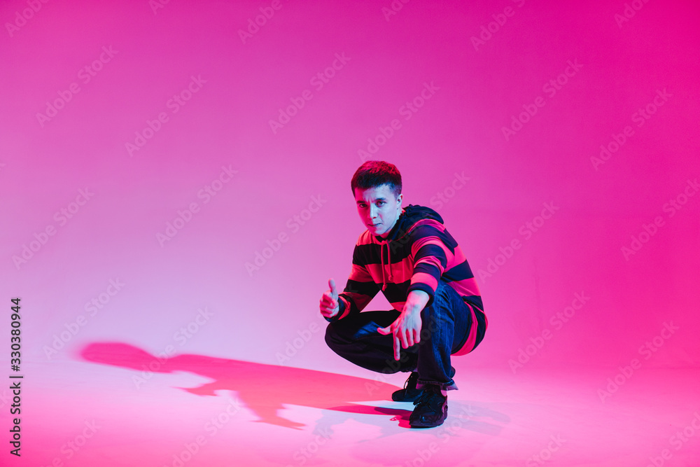 Young Man in a Jumper Dancing Contemporary Dance in Studio. Breakdancing. Dance School Poster. Copy Space. Battle competition announcement. Pink and Blue Background. Young Man in a Jumper Dancing Contemporary Dance in Studio. Breakdancing. Dance School Poster. Copy Space. Battle competition announcement. Pink and Blue Background.