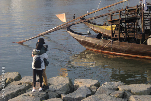 Silhueta de casal de namorados a passear num dia de inverno na zona da ribeira, margem do rio d'ouro no porto perto de dois barcos rabelos photo