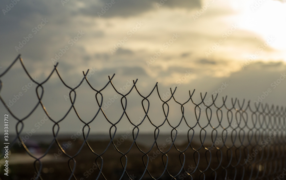 Restricted area concept. A metal mesh fence enclosing a restricted area (quarantine, prison, production area) Restricted area concept. A metal mesh fence enclosing a restricted area (quarantine, prison, production area)