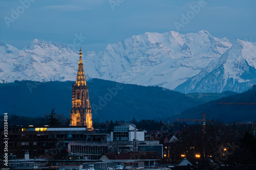 BERN, SWITZERLAND - MARCH 8, 2020: Night view of the iilluminated tower in Bern with the Alps in the background