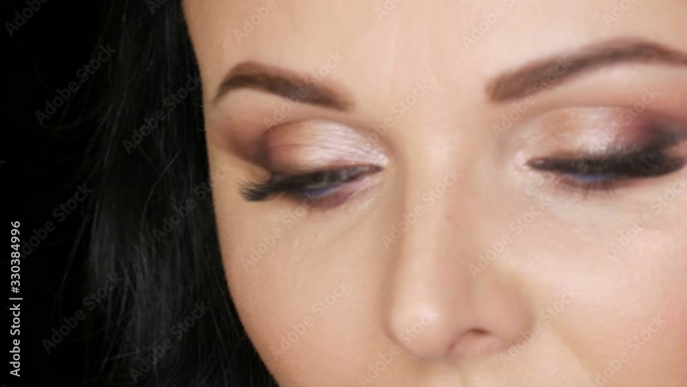 Close-up portrait of the face of a beautiful young woman with bright evening make-up and blue eyes, smoky eyes make on a black background in a studio. Close-up portrait of the face of a beautiful young woman with bright evening make-up and blue eyes, smoky eyes make on a black background in a studio.