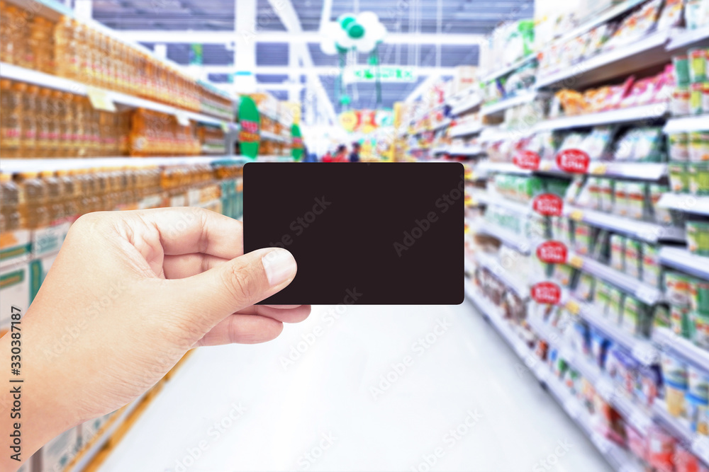 Hand holding black card with supermarket