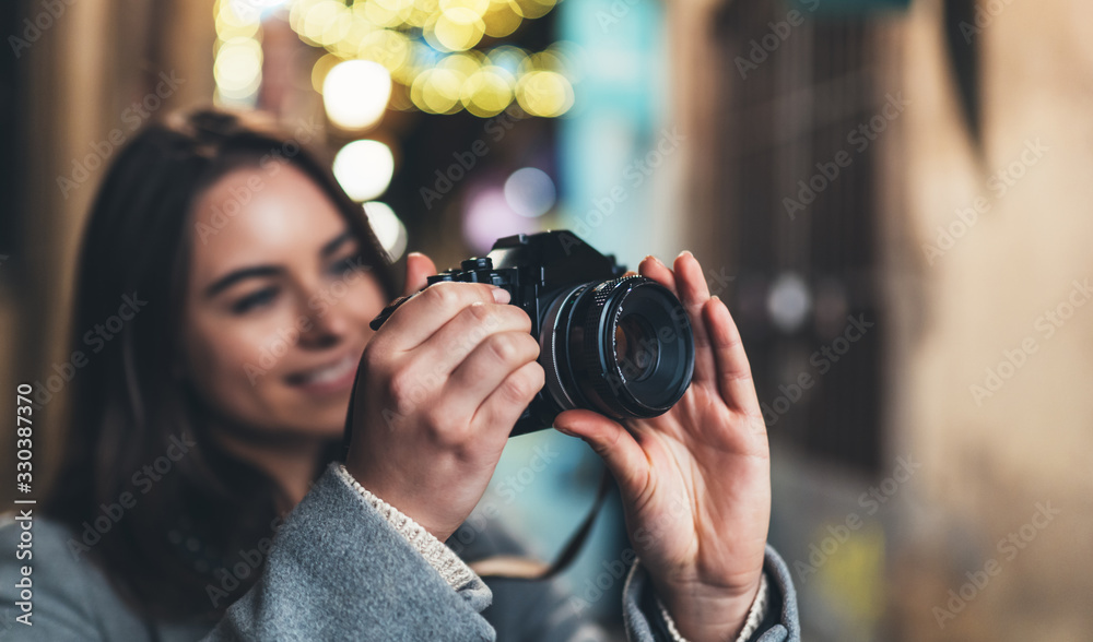 Photographer girl with retro camera take photo on background bokeh light in night city, Blogger photoshoot concept. Tourist  photo hobby. Outdoor portrait smile woman with video technology.