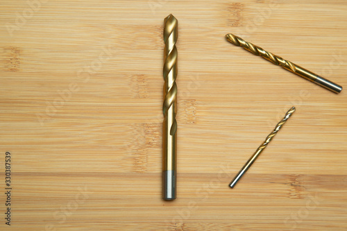 Drills on metal on a wooden background. A tool to work with.