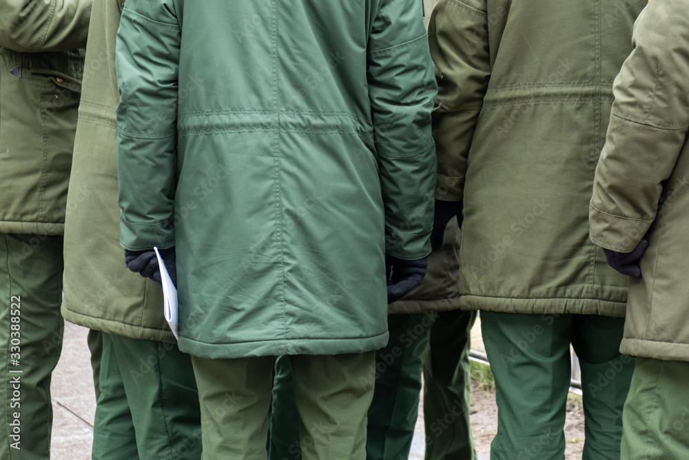 Several soldiers stand and talk in the city dressed in warm military clothing. Several soldiers stand and talk in the city dressed in warm military clothing.