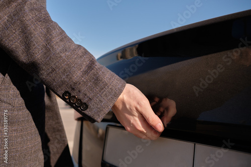 A man opens the trunk of a car on the street.