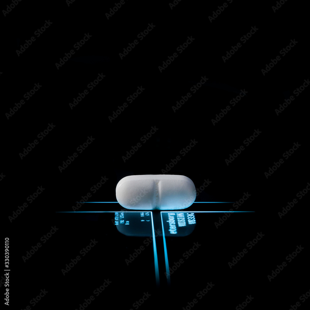 one white pill on luminous light blue lines with blurred data on a black background with reflection