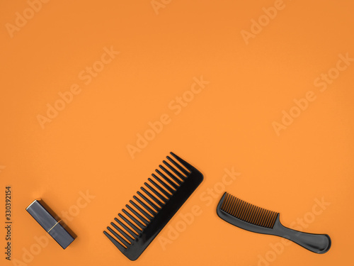 Combs and lipstick on an orange background.