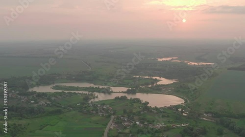 spectacular and very colorful sunset over the a lake with an island in the middle glistens in the sun and curls like a snake - Cityscape Aerial Flight photo