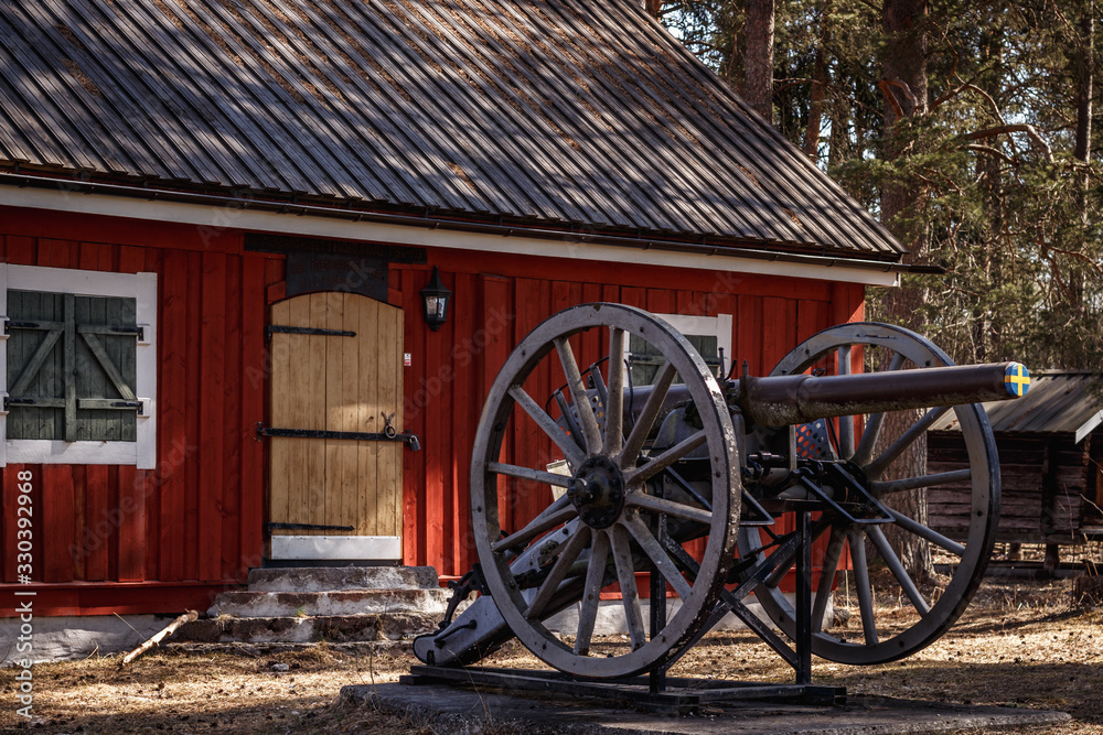 Obraz premium An old cannon next to a historic house in the woods